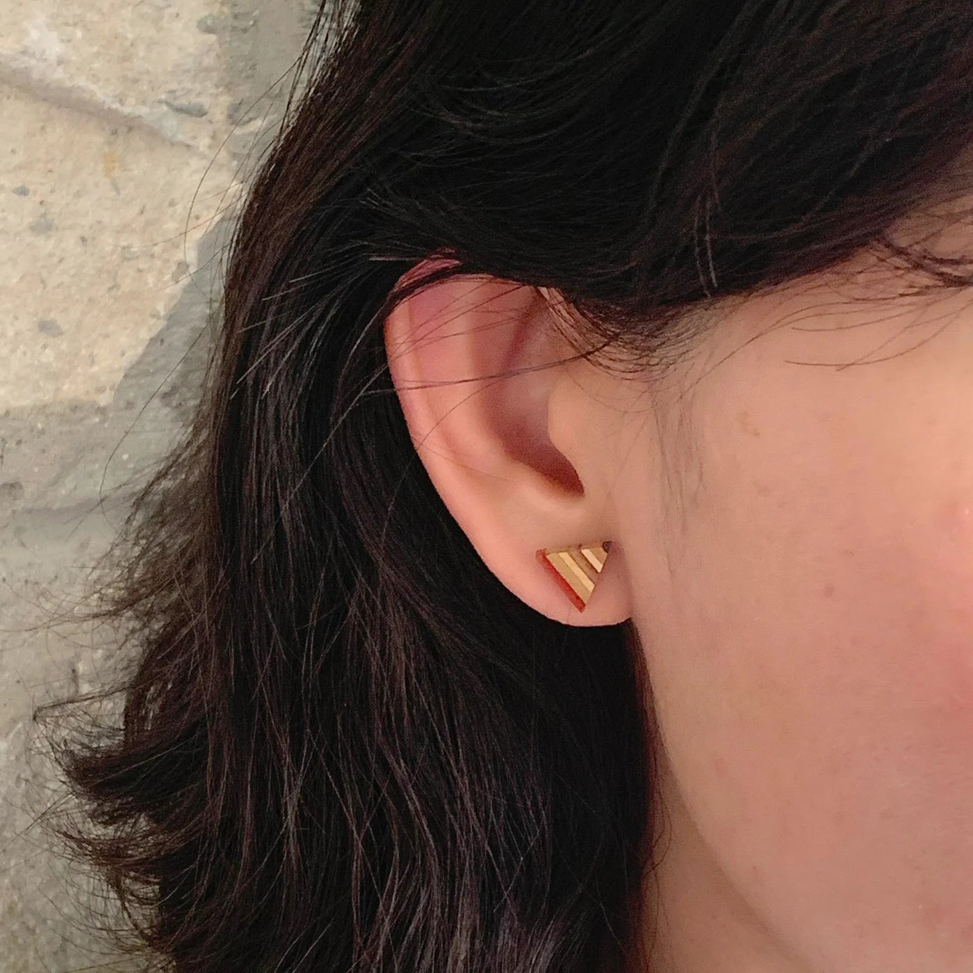 Model wearing a triangle striped stud earring. Earring is handmade from recycled skateboard. 